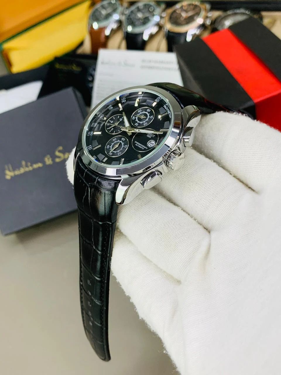 chronograph-style timepiece with a white dial and gold-tone accents.